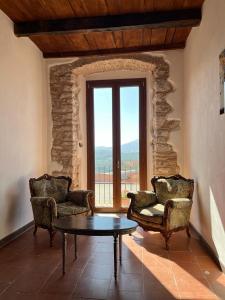 a living room with two chairs and a table and a window at DOMUS VELA in Fornelli