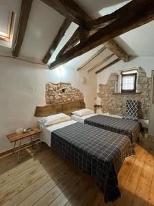 two beds in a room with a stone wall at DOMUS VELA in Fornelli