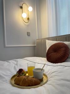 a tray with a drink and a plate of food on a bed at Apartman Vasia Subotica in Subotica