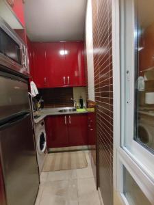 una pequeña cocina con armarios rojos y fregadero en Estudio Lorenzo Acogedor en Madrid