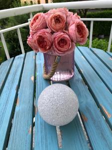 un vase de roses roses assises sur une table de pique-nique bleue dans l'établissement Ferienwohnung mit Charme, à Eurasburg