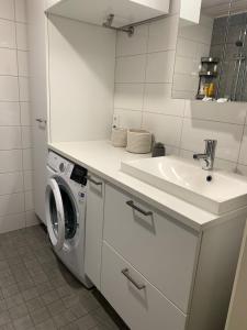 biała łazienka z umywalką i pralką w obiekcie Modern one bedroom apartment nearby Airport w mieście Vantaa