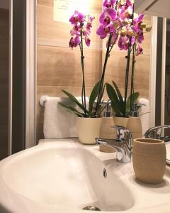 a bathroom sink with two vases with flowers on it at Casa Speri in Peschiera del Garda