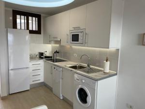 - une cuisine blanche avec un évier et un lave-vaisselle dans l'établissement Achacay Sunset Apartment, à Los Cristianos