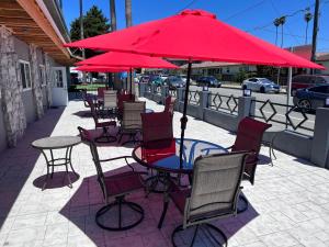 um grupo de mesas e cadeiras sob um guarda-sol vermelho em Surf City Inn & Suites em Santa Cruz