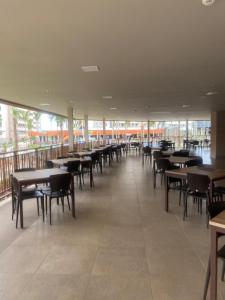 una sala da pranzo con tavoli, sedie e finestre di Apartamento dentro de resort próximo do Thermas dos Laranjais a Olímpia