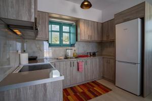 a kitchen with wooden cabinets and a white refrigerator at Sugar Stone House in Pyrgos Dirou