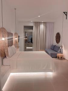 a white bedroom with a large bed and a couch at Delfini Beach Hotel & Suites in Archangelos