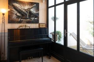a piano in a room with a painting on the wall at La Martinoise Patio in Saint-Martin-de-Ré