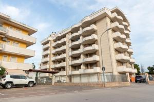 um grande edifício de apartamentos com um carro estacionado na frente em Casa di Franco em Alba Adriatica
