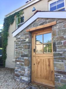 una puerta de garaje de madera en una casa de piedra en Efail Y Garn, en Swansea