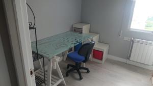 a desk with a blue chair and a glass table at Foz Playas in Foz +2 photos