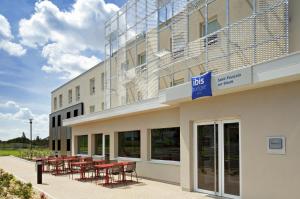 a building with tables and chairs outside of it at ibis budget Saint Pourcain in Saint-Pourçain-sur-Sioule
