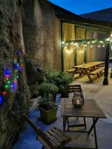 a patio with a table and a picnic table with lights at L'Orgelétaine : Grande Maison au milieu des Lacs du Jura in Orgelet