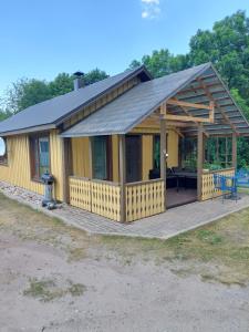 une grande maison jaune avec une terrasse en bois dans l'établissement jõekalda kodumajutus, à Häädemeeste