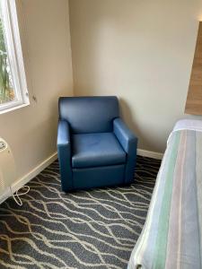 uma cadeira azul num quarto ao lado de uma cama em Dunes Motel Hillsboro em Hillsboro