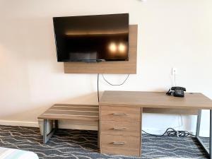 a room with a desk and a tv on a wall at Dunes Motel Hillsboro in Hillsboro
