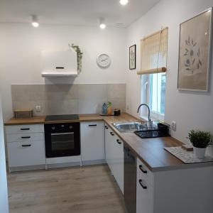 a kitchen with white cabinets and a sink and a stove at Apartament Pod Bzem Puck in Puck