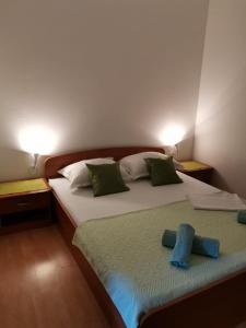 sypialnia z 2 łóżkami i białymi i zielonymi poduszkami w obiekcie Apartments Sretna w Gradacu