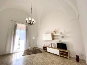 Sala de estar blanca con TV y lámpara de araña en La casa di Nina, en Surano