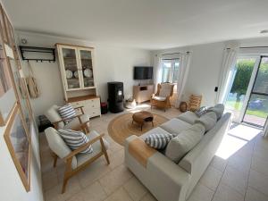 een woonkamer met een witte bank en stoelen bij Charlie & Chloé’s beachcondo ***** in De Haan
