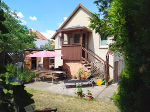 ein Haus mit einer Terrasse und einem rosa Regenschirm in der Unterkunft FeWo unter den Eichen in Wienrode