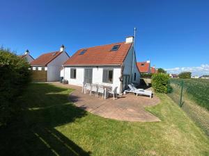 een wit huis met een tafel en stoelen in een tuin bij Charlie & Chloé’s beachcondo ***** in De Haan