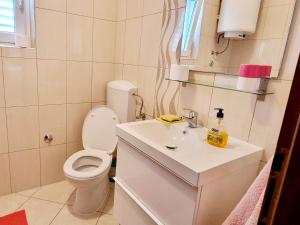a white bathroom with a toilet and a sink at Apartman Val in Rogoznica +21 photos