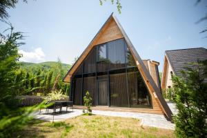 a house with a triangular roof with glass windows at Pine Villas Brezovice in Brezovica