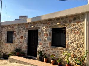 a stone house with potted plants in front of it at Oikia Stone House in seaside Kalo Chorio in Agios Nikolaos