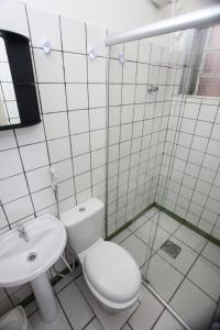 a white bathroom with a toilet and a sink at Hotel Tapajós in Cuiabá