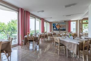 a dining room with tables and chairs and large windows at Hotel Silver in Milano Marittima