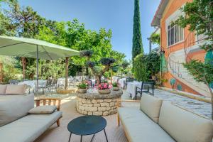 Logis Hotel Le Blason de Provence في مونتيو: فناء به كنب أبيض ومظلة