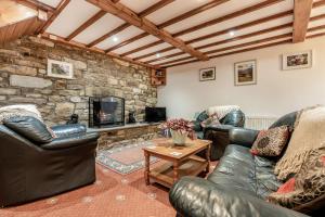 Milnthorpe的住宿－Brant View，客厅配有皮革家具和石墙