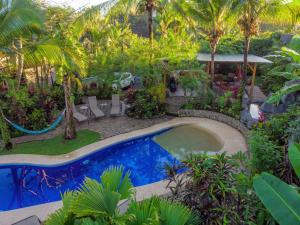 a swimming pool in a yard with palm trees at Villas Oasis in Manuel Antonio