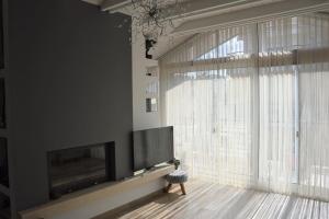 uma sala de estar com televisão e uma grande janela em Ηλιόλουστη σοφίτα Scandinavian αισθητικής. em Xanthi