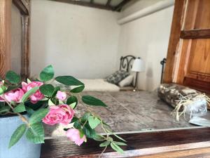 una habitación con una mesa con un jarrón con rosas rosas en Casa rural en el Parque Nacional de Garajonay en la Isla de La Gomera, Alonso y Carmen en Santa Cruz de Tenerife