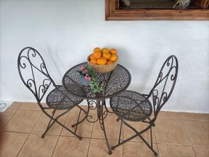 einen Tisch und Stühle mit einer Schüssel Orangen darauf in der Unterkunft Casa rural en el Parque Nacional de Garajonay en la Isla de La Gomera, Alonso y Carmen in Santa Cruz de Tenerife