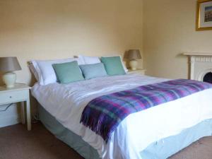 a bedroom with a large white bed with blue pillows at Woodside Cottage in Snainton