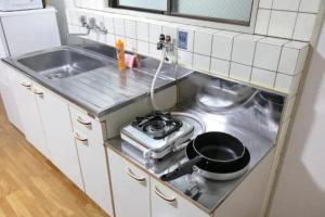 Una pequeña cocina con estufa y fregadero. en Ash Court Joto, en Osaka 41 fotos más