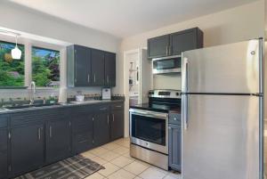 a kitchen with black cabinets and a stainless steel refrigerator at 3 min to Beach, Game Room, Hot tub & Firepit in Traverse City