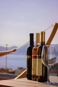 três garrafas de vinho e um copo de vinho numa mesa em Vertmont Villa em Sveti Stefan
