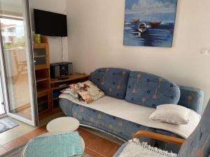 un salon avec un canapé bleu et une télévision dans l'établissement Apartment Near The Beach, à Privlaka