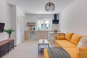 a living room with a yellow couch and a kitchen at Apartamentos Playa de Finisterre in Fisterra