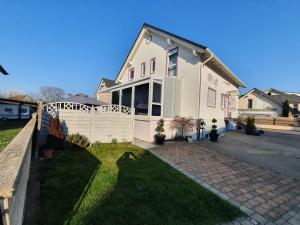 a white house with a fence in the yard at Pension Kuhn in Rust