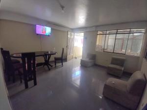 sala de estar con mesa, sillas y TV en BACKPAKERS MIRADOR, en Huaraz