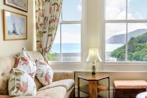 a living room with a couch and two large windows at Clooneavin Apartment 6 in Lynmouth