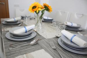 a table with plates and a vase with a yellow flower at Fuente Lebana Labradores in Facinas