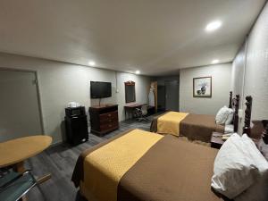 a hotel room with two beds and a flat screen tv at Mid Towne Inn & Suites in San Antonio