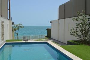 a swimming pool with the ocean in the background at Wave Resort in Al Khobar
